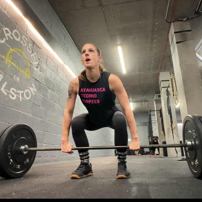 Woman performing a clean with a barbell in a gym setting